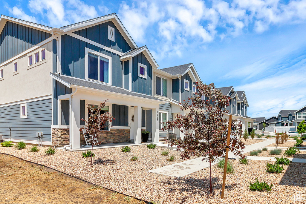 View of front of house with board and batten siding, covered porch, a residential view, and stone siding