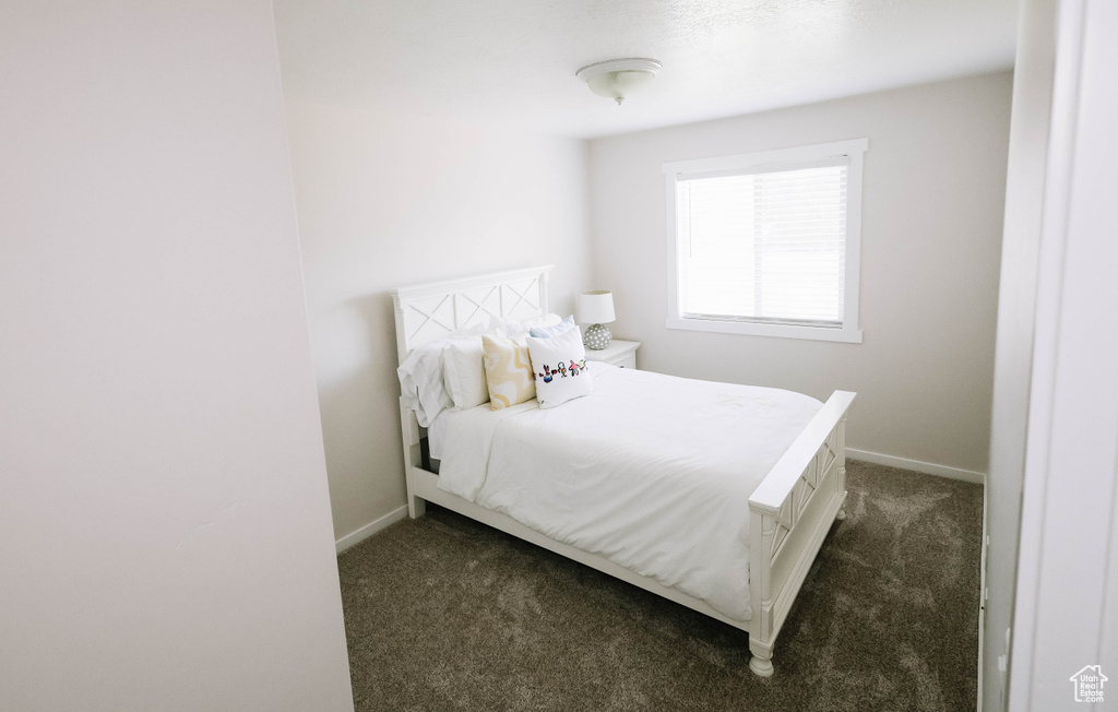 Bedroom featuring dark colored carpet and baseboards
