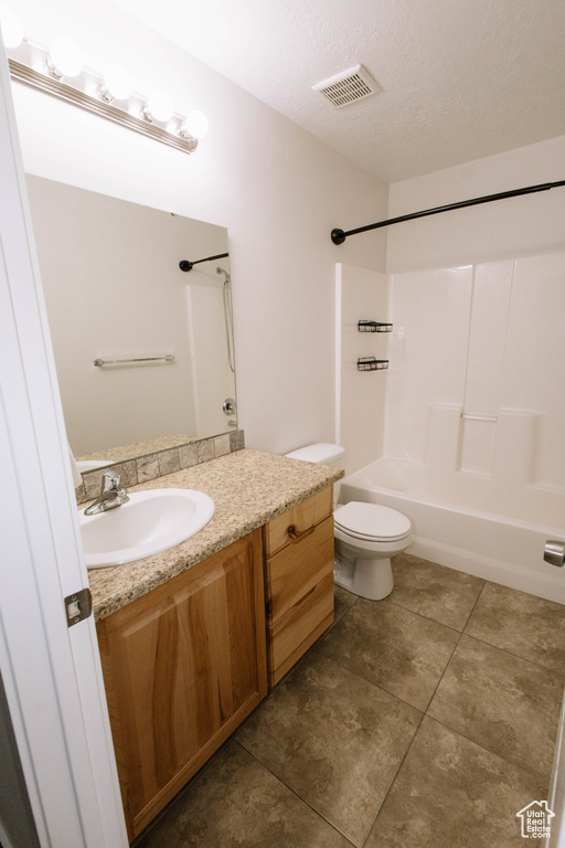 Bathroom with vanity, bathing tub / shower combination, tile patterned flooring, toilet, and a textured ceiling