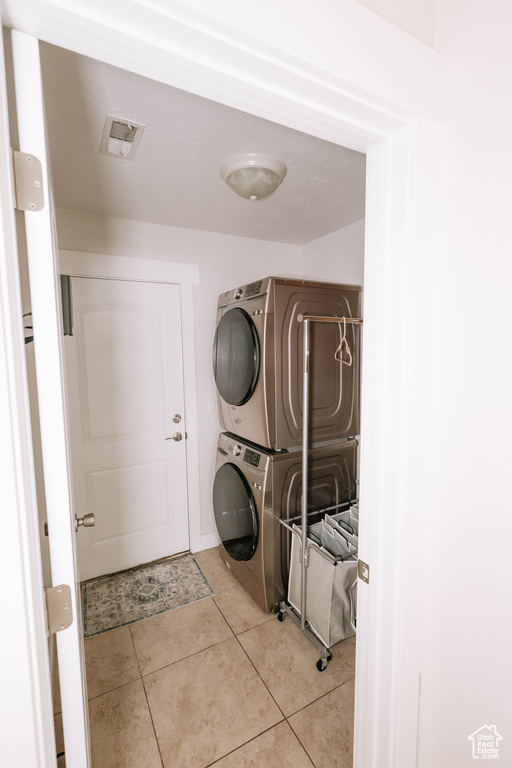 Laundry area with estacked washer and dryer and tile patterned floors