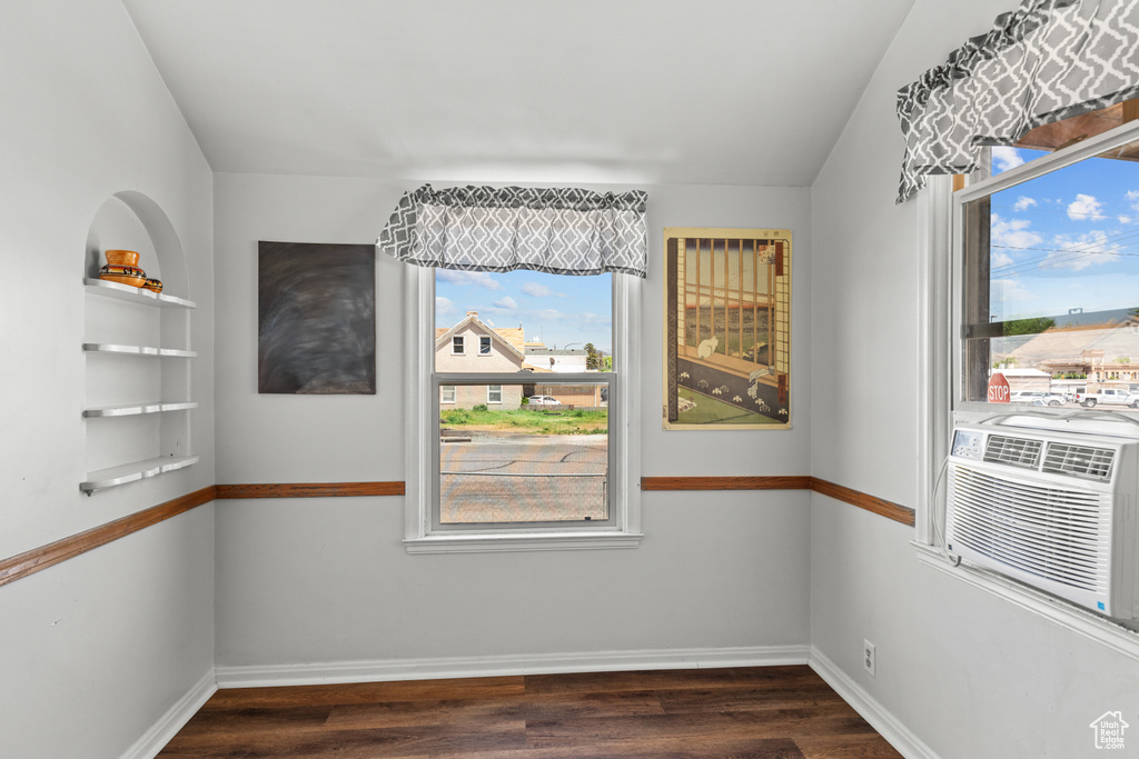 Unfurnished room featuring dark wood-style flooring, baseboards, and cooling unit