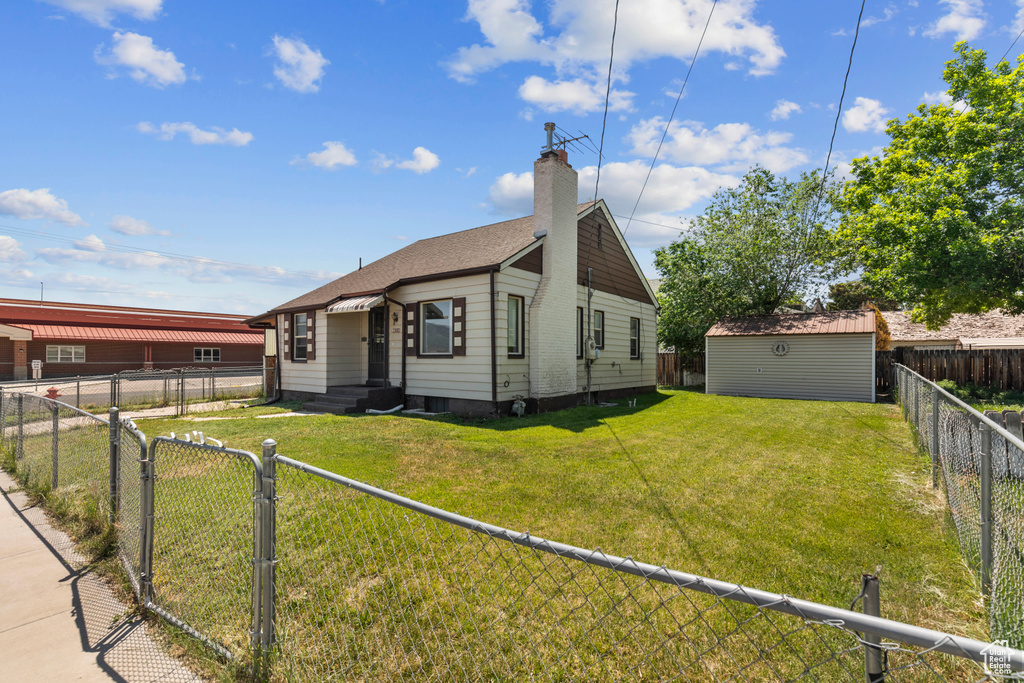 Rear view of property with a chimney, a shingled roof, a gate, and an outdoor structure