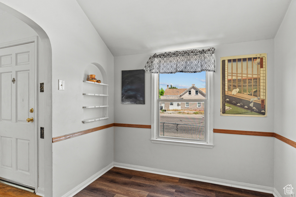 Foyer featuring arched walkways, dark wood-style flooring, and baseboards