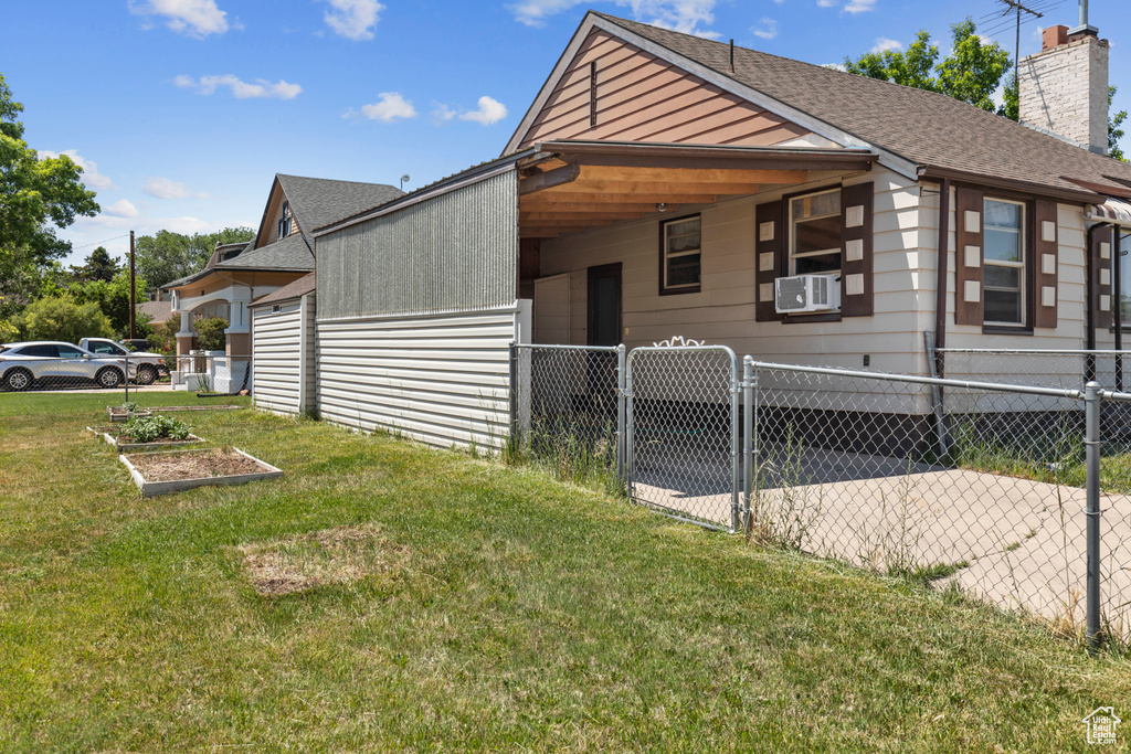 View of home\'s exterior with a gate, a chimney, cooling unit, and roof with shingles