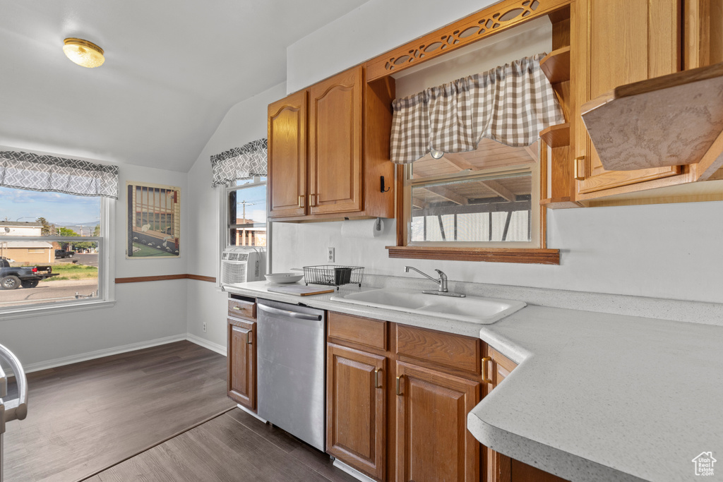 Kitchen featuring stainless steel dishwasher, a sink, lofted ceiling, light countertops, and dark wood-style floors