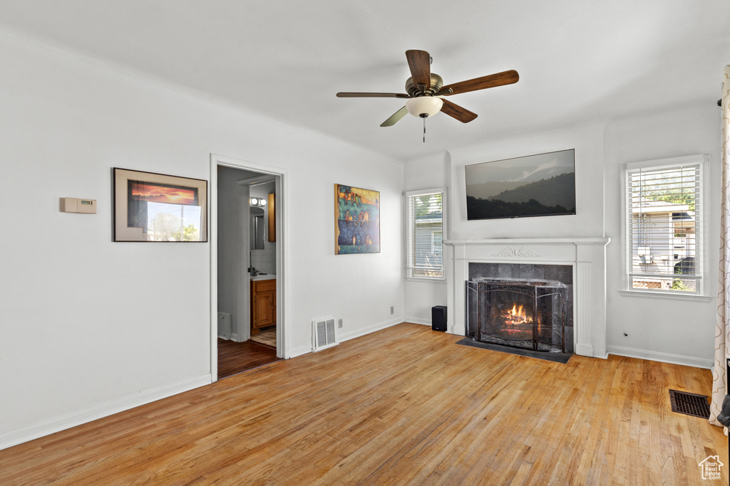 Unfurnished living room with a fireplace with flush hearth, light wood finished floors, healthy amount of natural light, and a ceiling fan