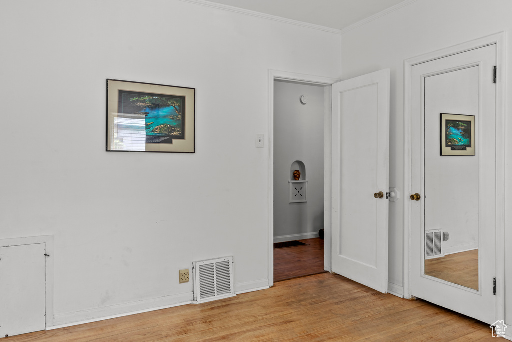 Unfurnished bedroom featuring crown molding, light wood-type flooring, and baseboards
