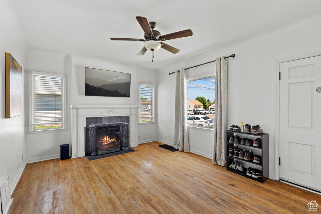 Living area featuring a high end fireplace, ceiling fan, wood finished floors, and baseboards
