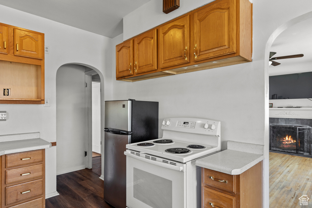 Kitchen with white electric range, arched walkways, a ceiling fan, and dark wood-style flooring