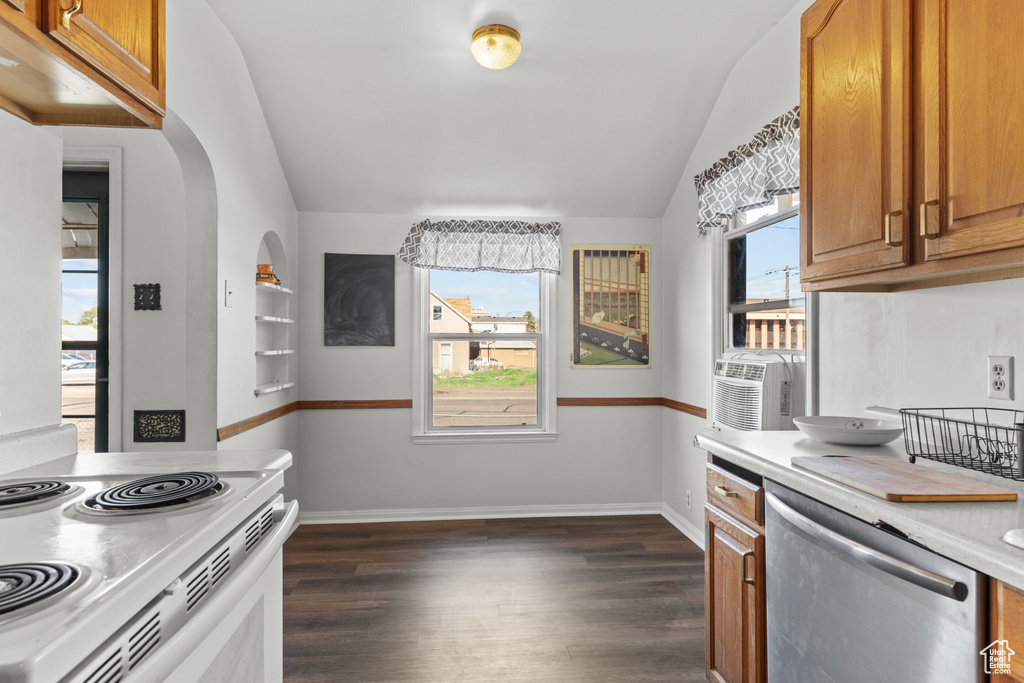 Kitchen with stainless steel dishwasher, vaulted ceiling, brown cabinetry, dark wood-style floors, and light countertops