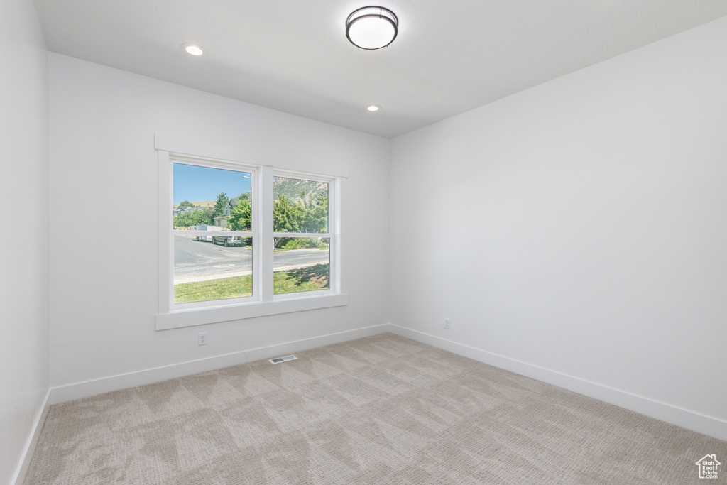 Empty room featuring light colored carpet, baseboards, and recessed lighting