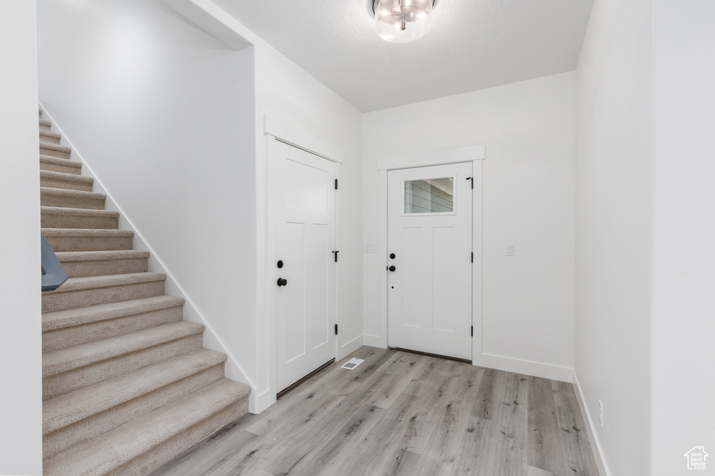 Entrance foyer with stairway, light wood-style flooring, and baseboards