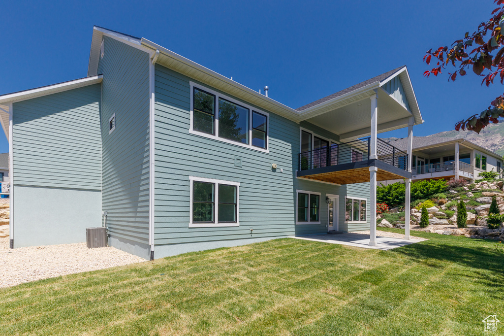 Rear view of house with a patio area, a yard, and a balcony