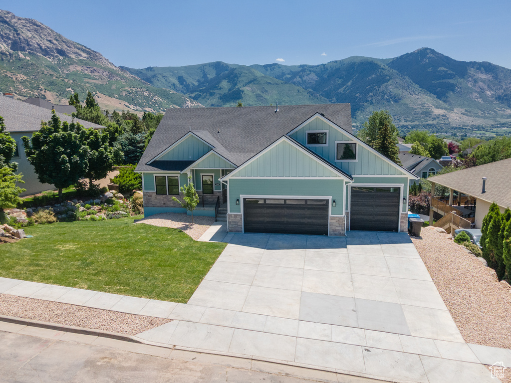 Craftsman-style house featuring board and batten siding, a front lawn, stone siding, and a mountain view