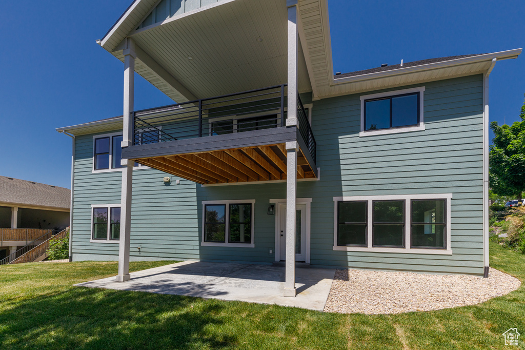 Back of house with a lawn, a balcony, and a patio