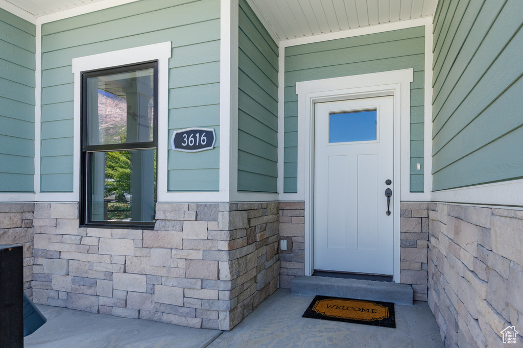 Entrance to property featuring stone siding and a porch
