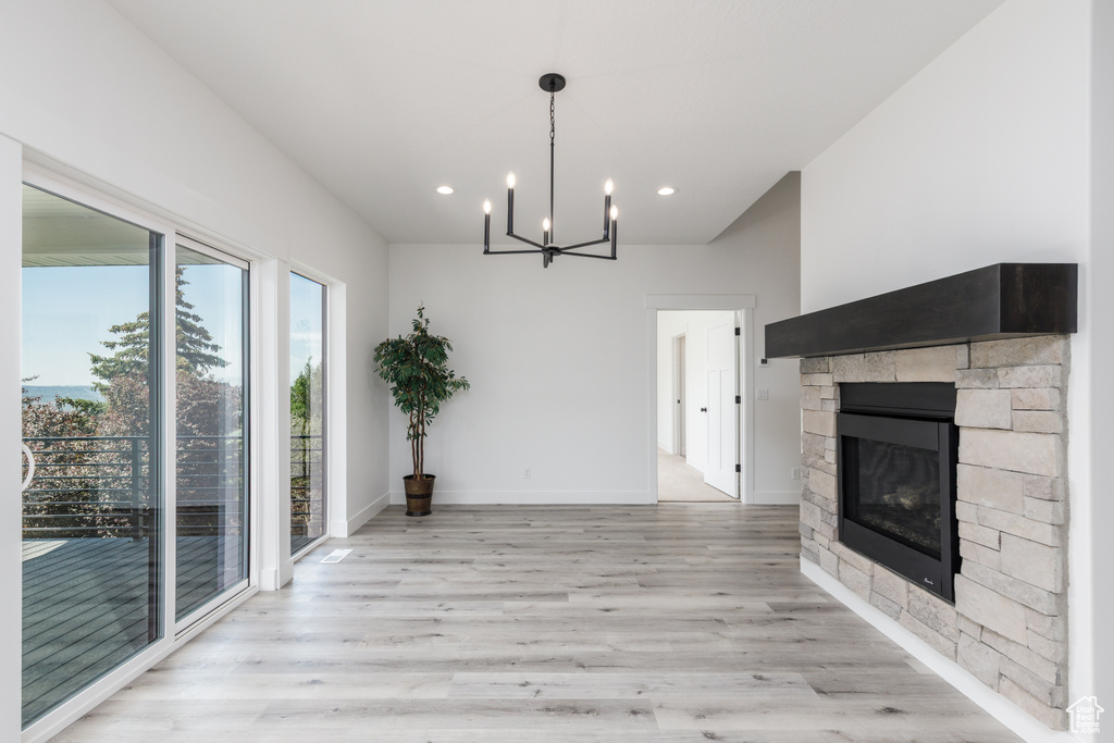 Unfurnished dining area with light wood-type flooring, a chandelier, recessed lighting, a fireplace, and baseboards