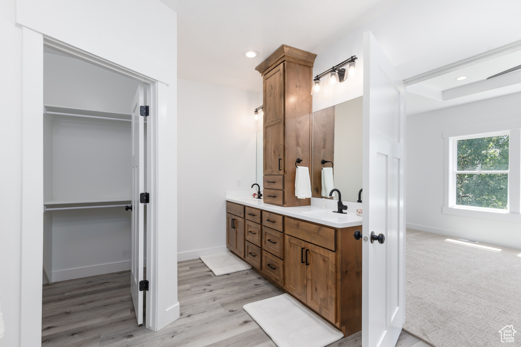 Full bathroom with double vanity, a spacious closet, wood finished floors, baseboards, and recessed lighting