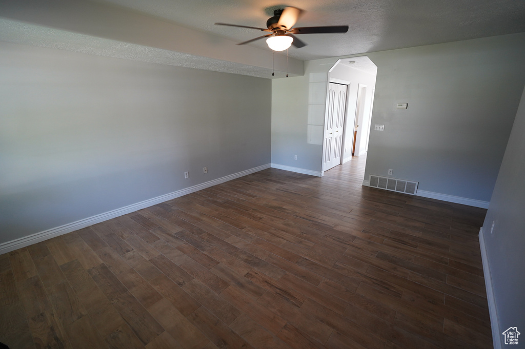 Spare room with ceiling fan, baseboards, and dark wood-style flooring