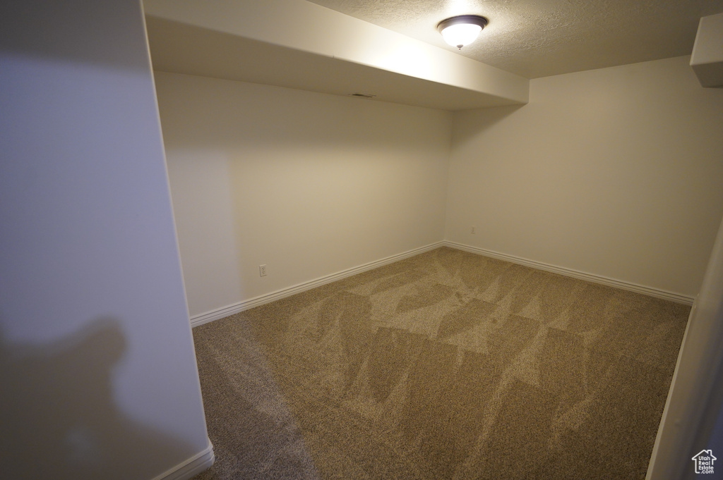 Finished below grade area featuring carpet floors, a textured ceiling, and baseboards