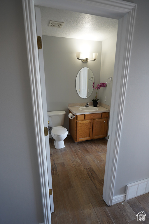 Bathroom featuring wood finished floors, vanity, and toilet