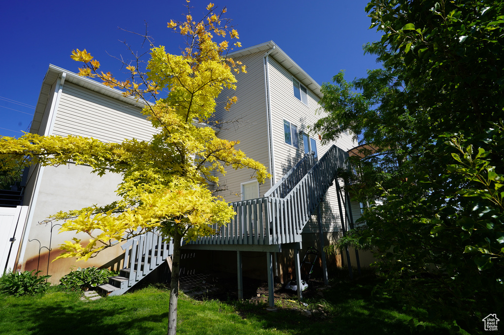View of side of home with stairway, a deck, and a lawn
