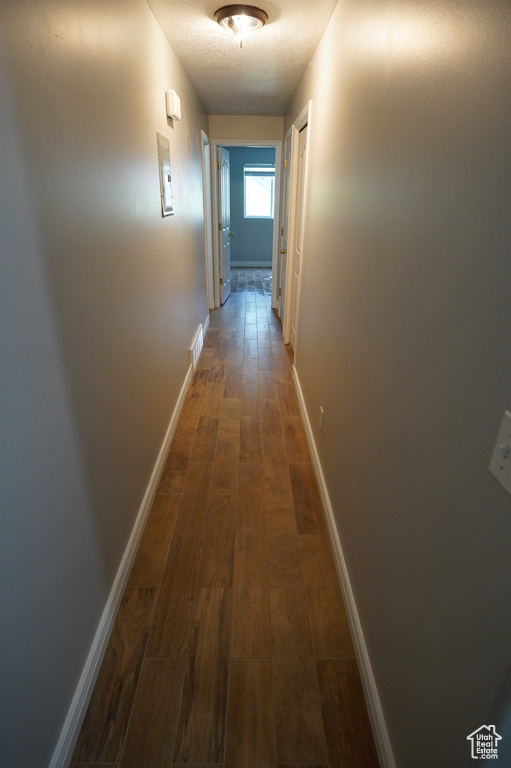 Hallway with dark wood-type flooring and baseboards