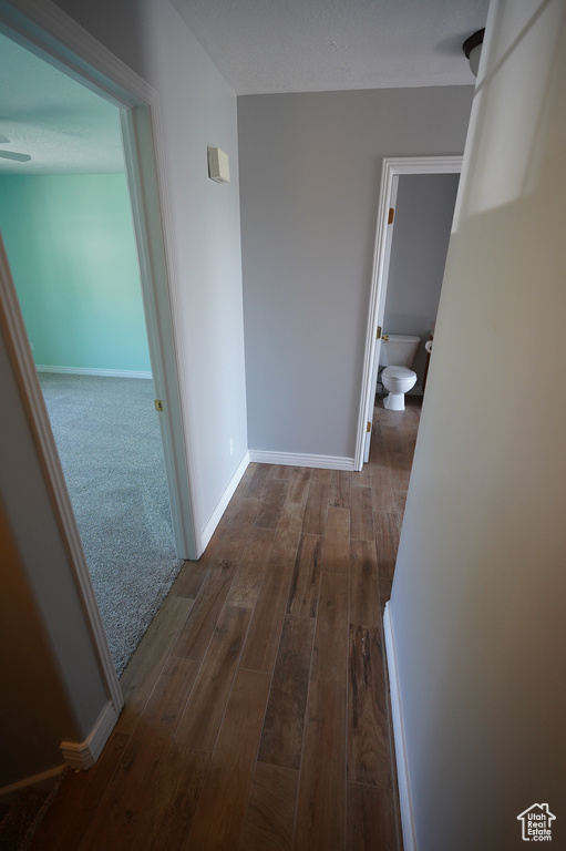 Hall featuring dark wood-style flooring and baseboards