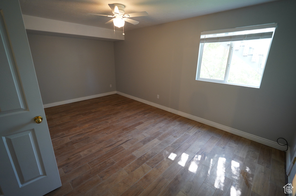 Unfurnished room featuring a ceiling fan, baseboards, and dark wood-type flooring