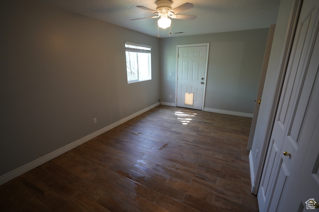 Unfurnished bedroom featuring baseboards, dark wood-type flooring, and a ceiling fan