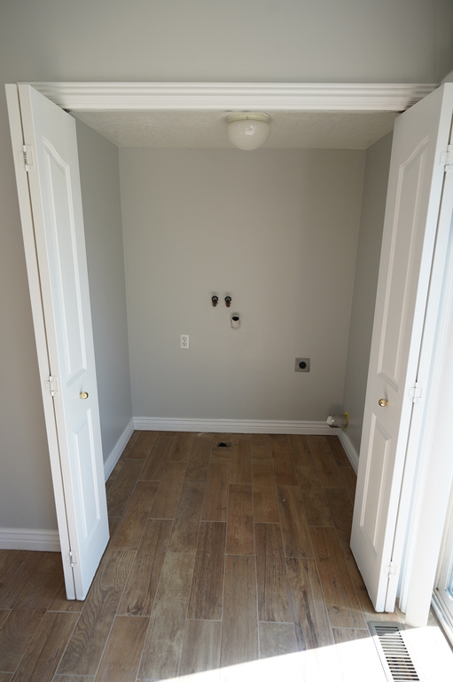 Washroom featuring hookup for an electric dryer, wood finished floors, washer hookup, and baseboards