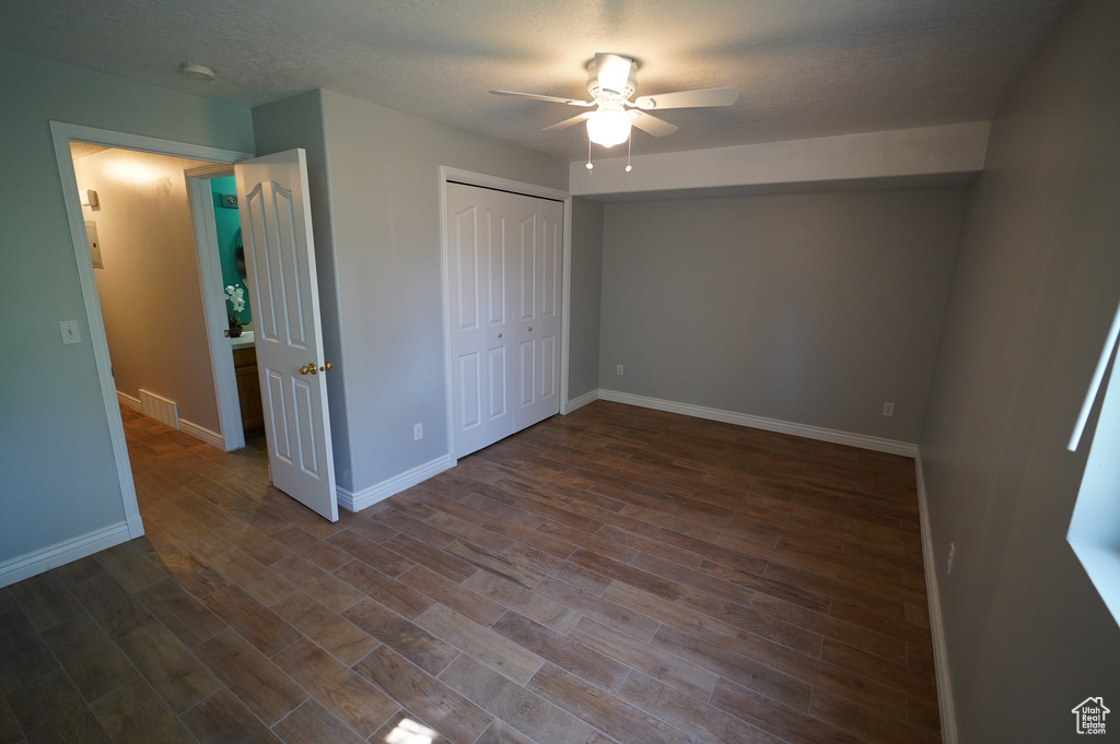 Unfurnished bedroom with baseboards, dark wood-style flooring, a closet, and ceiling fan