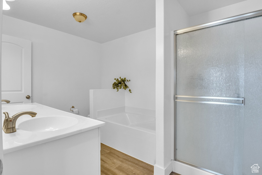 Full bath with a garden tub, wood finished floors, a stall shower, and double vanity