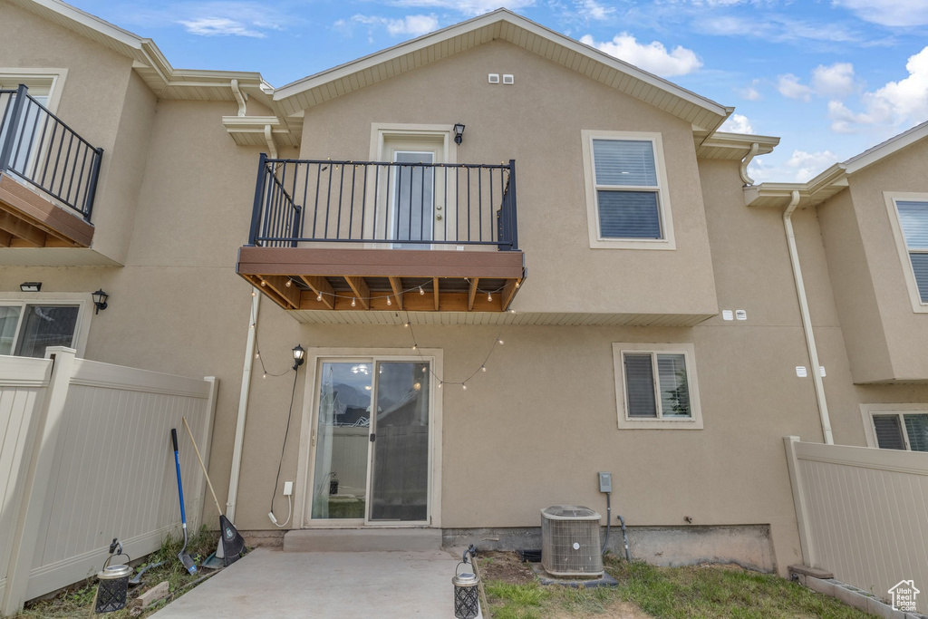 Back of house featuring a balcony, central AC, stucco siding, and a patio area