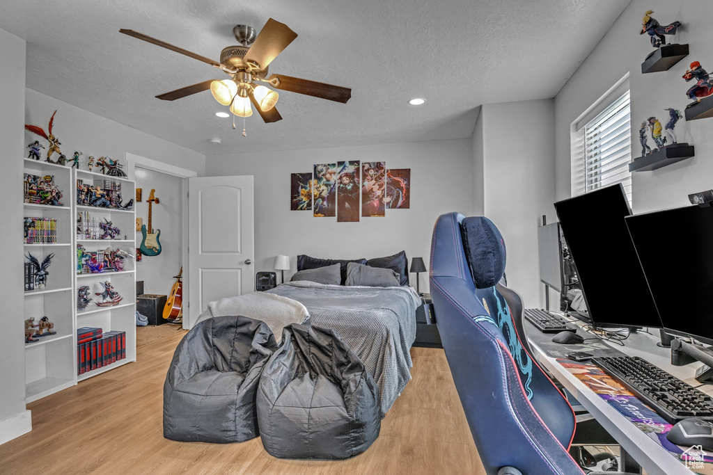 Bedroom featuring a textured ceiling, wood finished floors, an office area, a ceiling fan, and recessed lighting