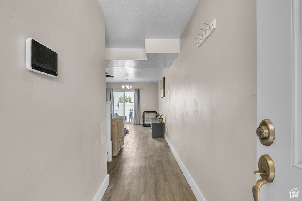 Corridor featuring wood finished floors, baseboards, and a textured ceiling