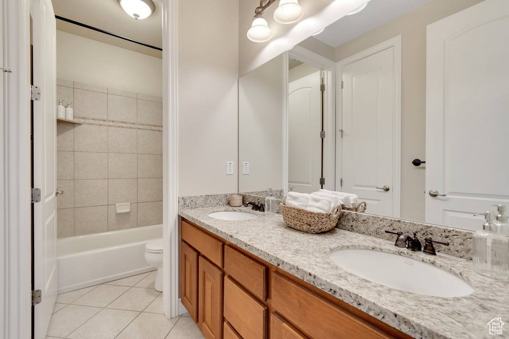 Full bathroom with double vanity, tile patterned floors, toilet, and shower / bathtub combination