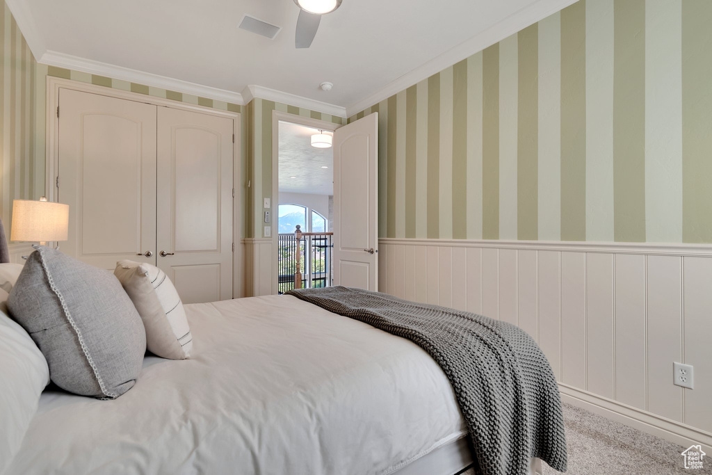 Bedroom featuring crown molding, a wainscoted wall, and a ceiling fan