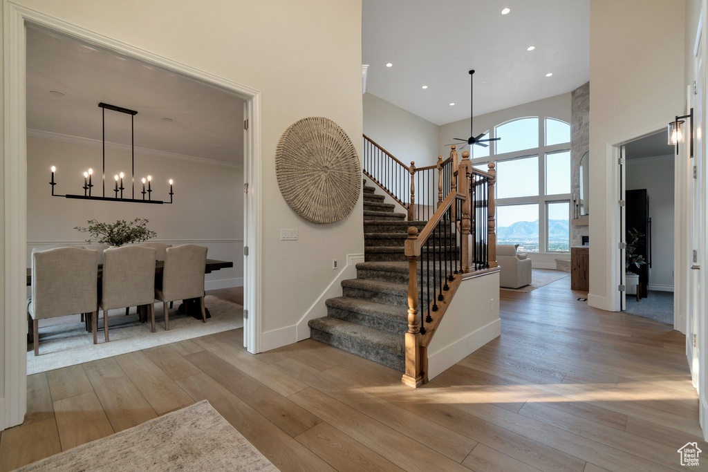 Stairway featuring a high ceiling, ceiling fan, a chandelier, wood finished floors, and baseboards