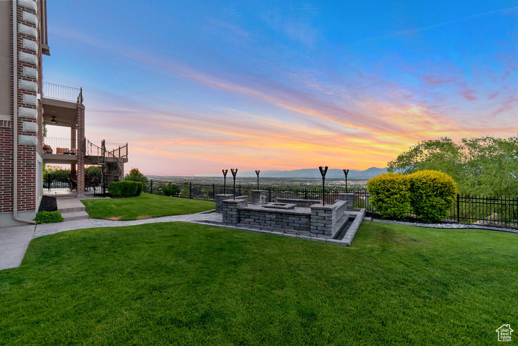 Yard at dusk featuring a fire pit, a mountain view, and a balcony