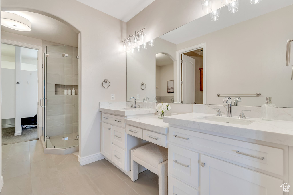 Bathroom with double vanity, a shower stall, tile patterned floors, and baseboards