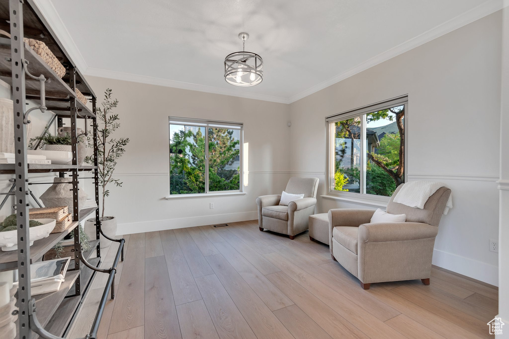 Living area featuring plenty of natural light, crown molding, light wood-type flooring, and baseboards