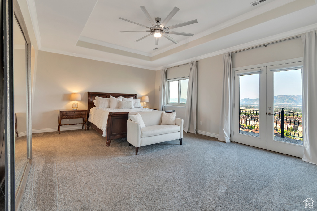 Carpeted bedroom featuring a tray ceiling, access to exterior, a mountain view, crown molding, and french doors