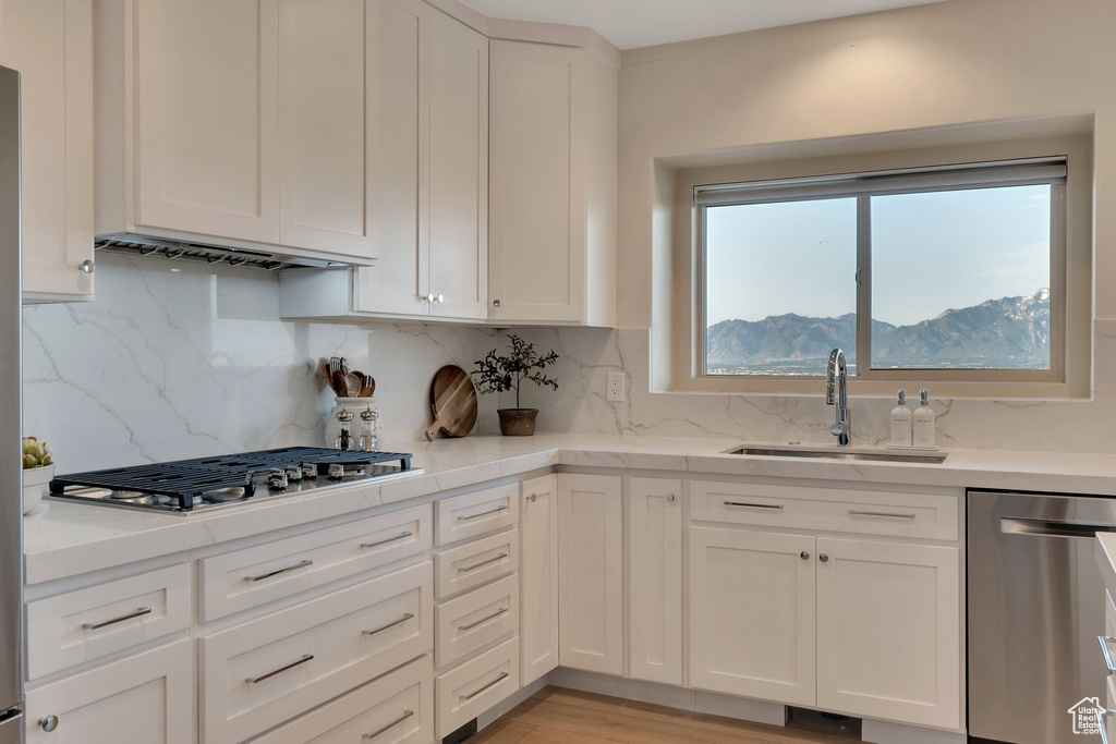 Kitchen featuring stainless steel appliances, a sink, and white cabinets