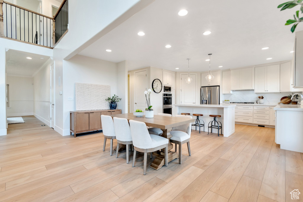 Dining room featuring light wood finished floors, recessed lighting, baseboards, and ornamental molding