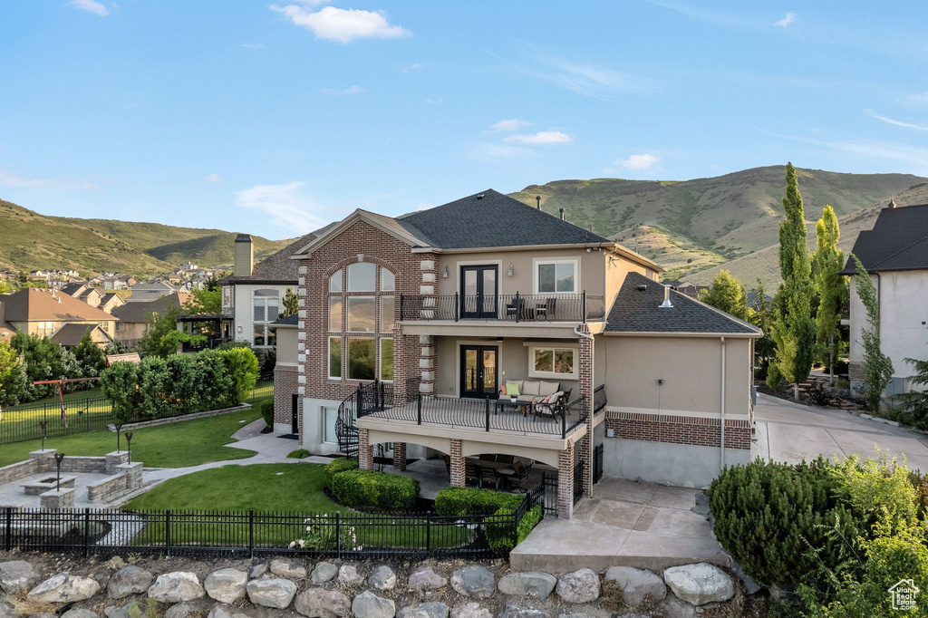 Rear view of property featuring a balcony, french doors, a patio, and a mountain view