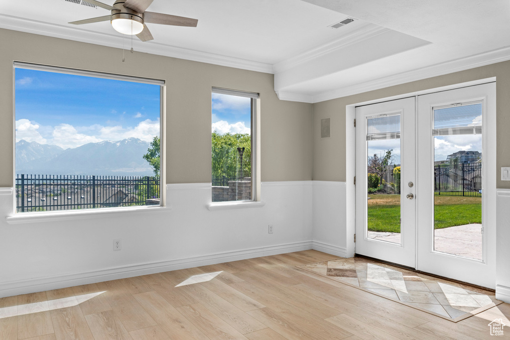 Spare room with french doors, ornamental molding, light wood-type flooring, healthy amount of natural light, and ceiling fan