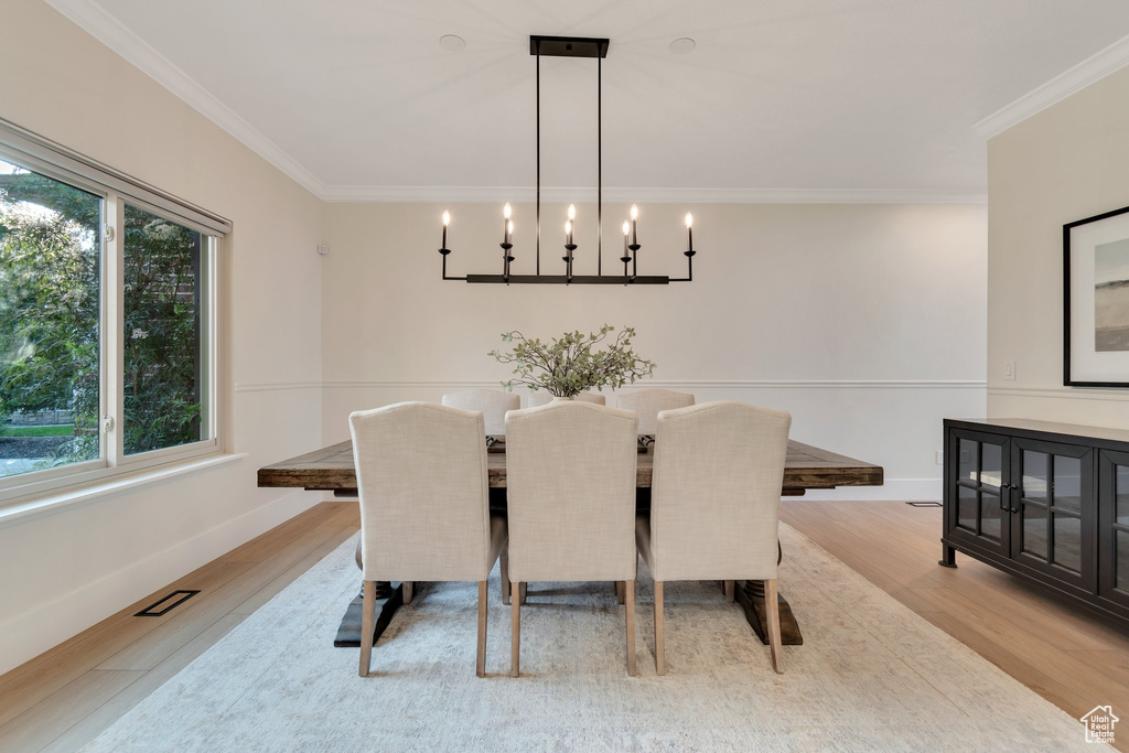Dining space with wood finished floors, ornamental molding, a chandelier, and baseboards