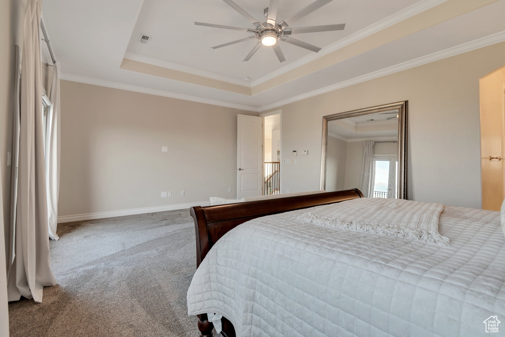 Bedroom featuring a raised ceiling, carpet, crown molding, and baseboards