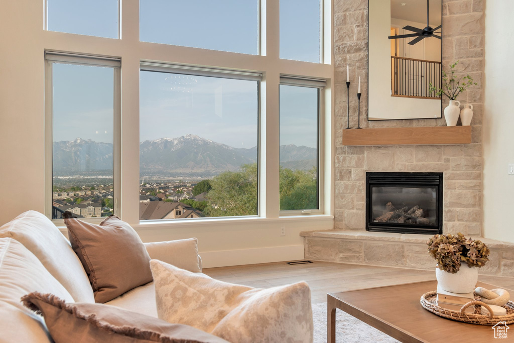 Living room featuring wood finished floors, a mountain view, a high ceiling, ceiling fan, and a stone fireplace